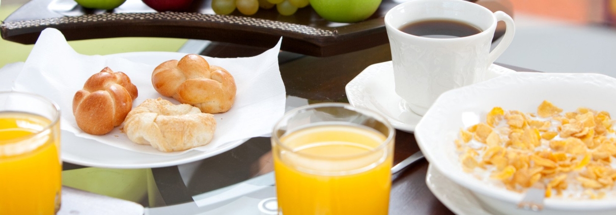 Background image of a table set with nutritious food. Contains fruits, coffee, juice, bread, and cereal