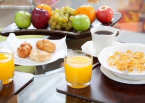 Background image of a table set with nutritious food. Contains fruits, coffee, juice, bread, and cereal