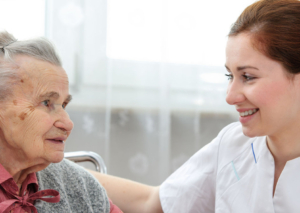 Caregiver helping female resident in a nursing-home-like facility.