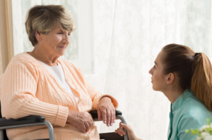 personalized-senior-care-facility-upendo-house Caregiver and resident smiling at each other in a nursing-home-like facility.